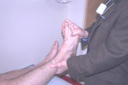 I was sitting up right, he then pushed on my foot with his right hand to see how far it would bend.